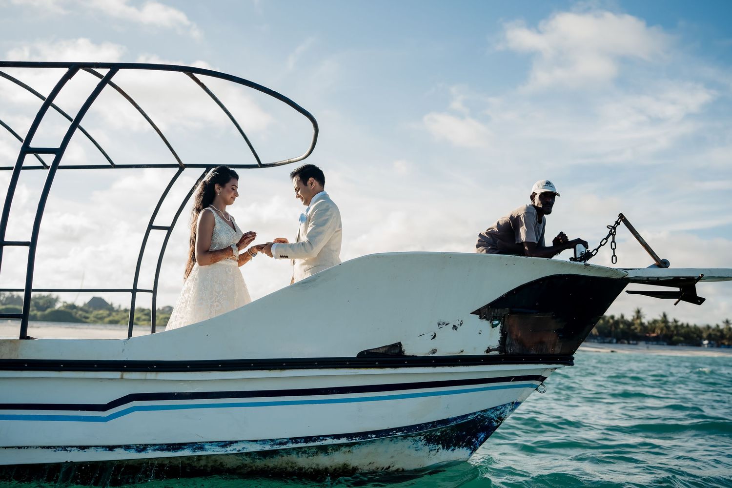 A wedding ceremony takes place on a boat in beautiful turquoise waters under blue skies.