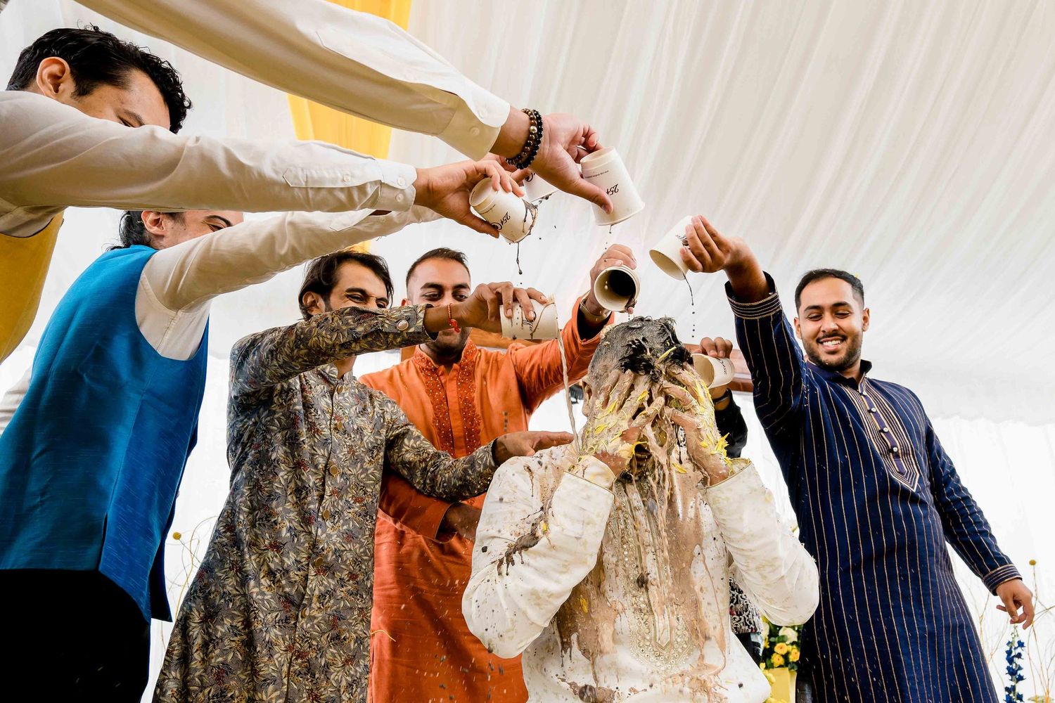 Celebratory moment at a wedding with guests in traditional attire throwing confetti and dancing.