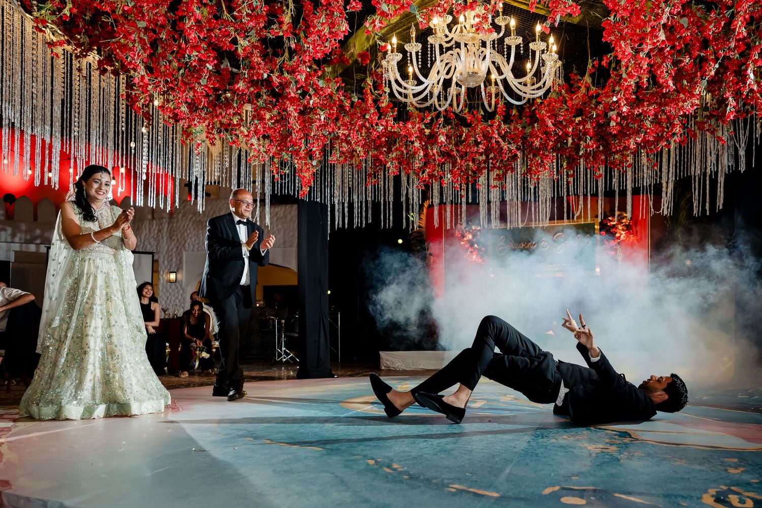 Wedding reception with dramatic red floral ceiling and chandelier as dancers perform.