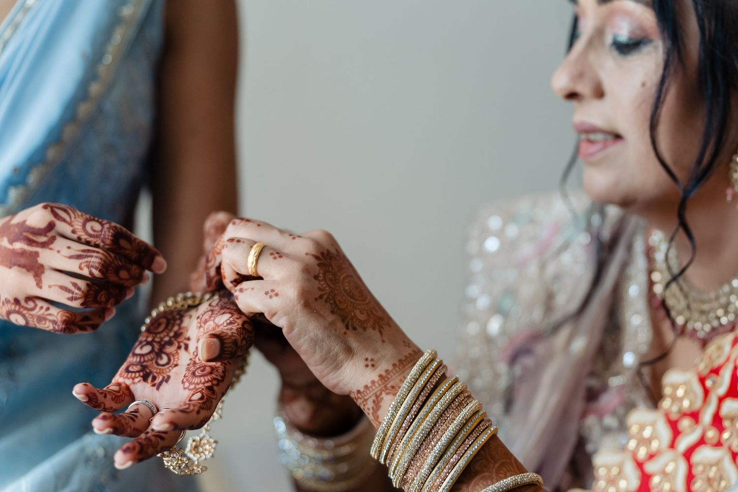 Detailed view of hands with henna and bangles during Indian wedding preparations.