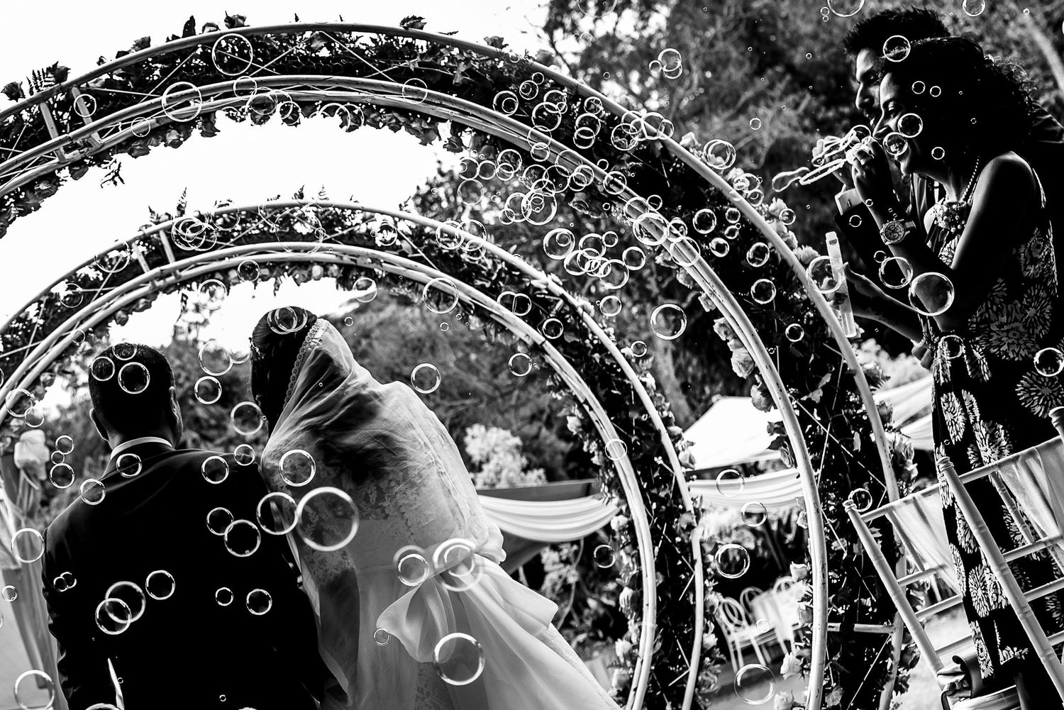 Artistic black and white wedding photo with decorative circular bokeh overlay effects.
