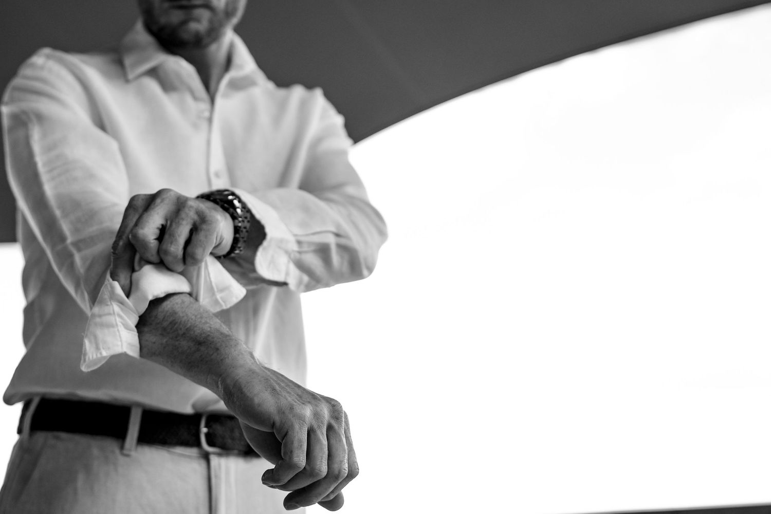Close-up shot of hands adjusting formal white shirt cuffs.