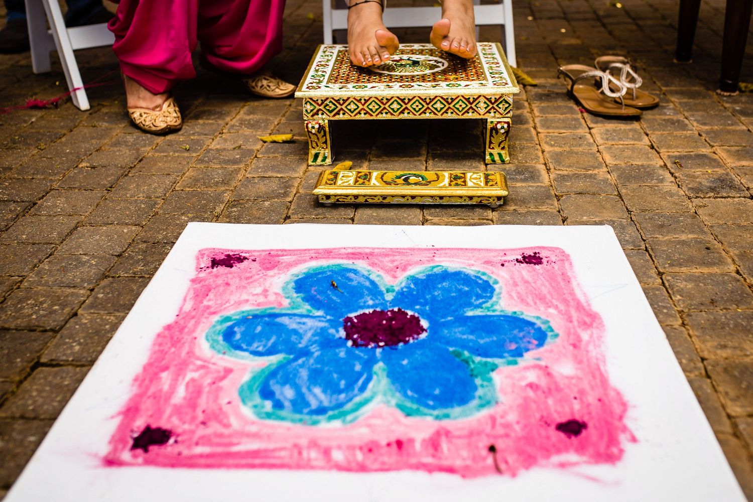 Colorful artwork being created on the ground showing a blue butterfly design against a pink background.