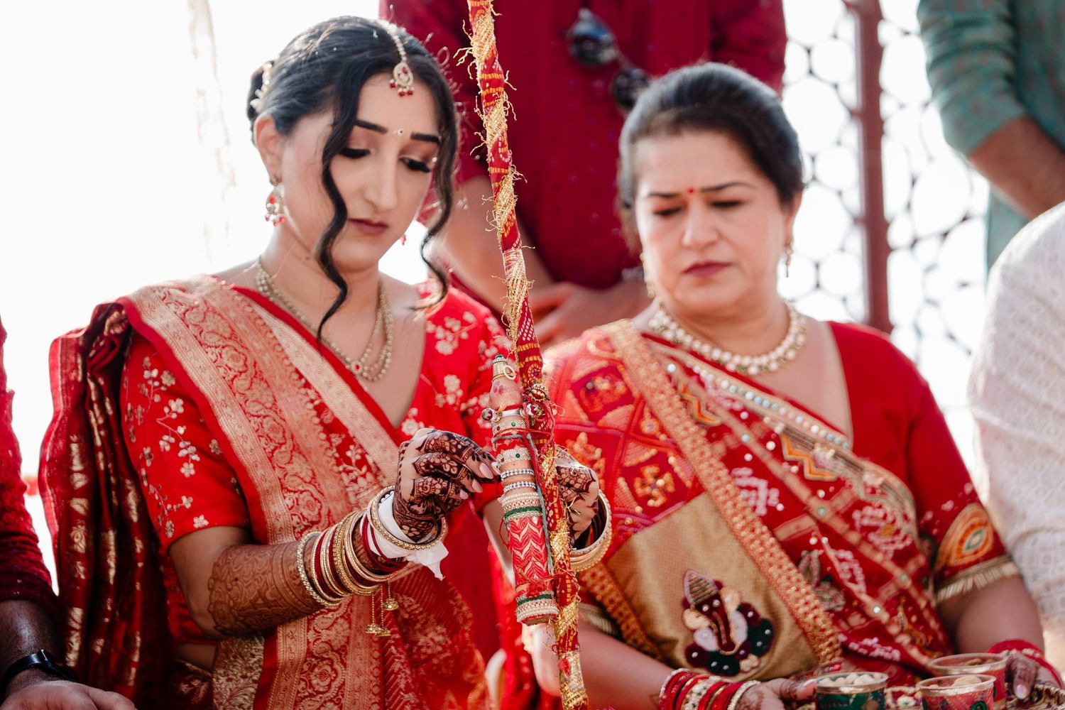 A traditional Indian wedding ceremony with people wearing vibrant red and gold attire during an intimate cultural celebration.