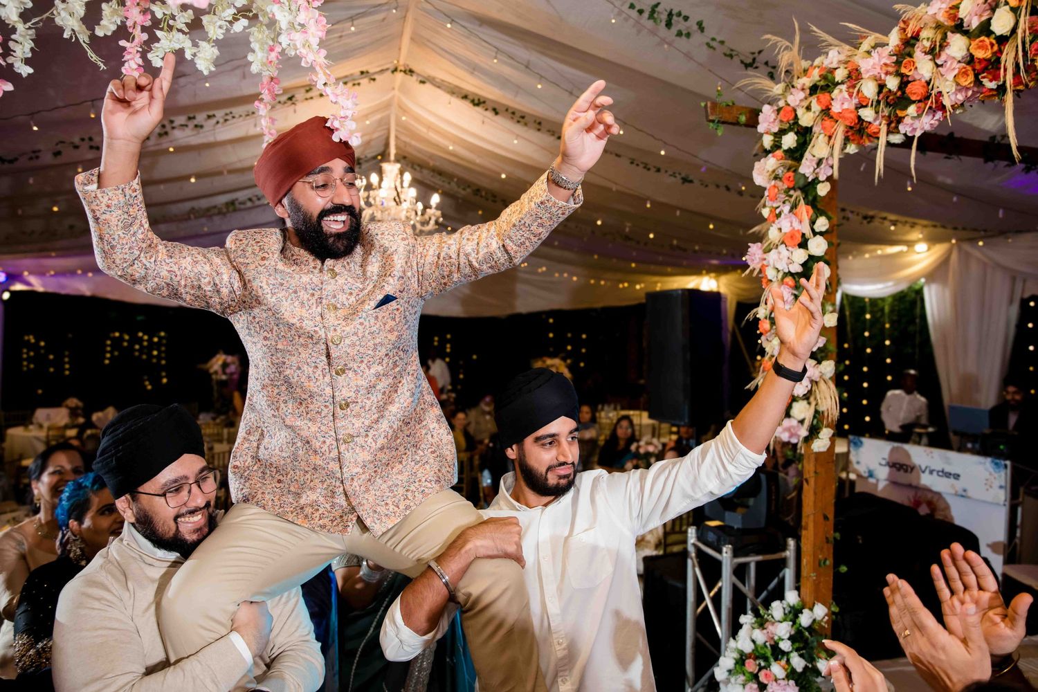 Energetic celebration at a wedding reception with people lifting someone in celebration.