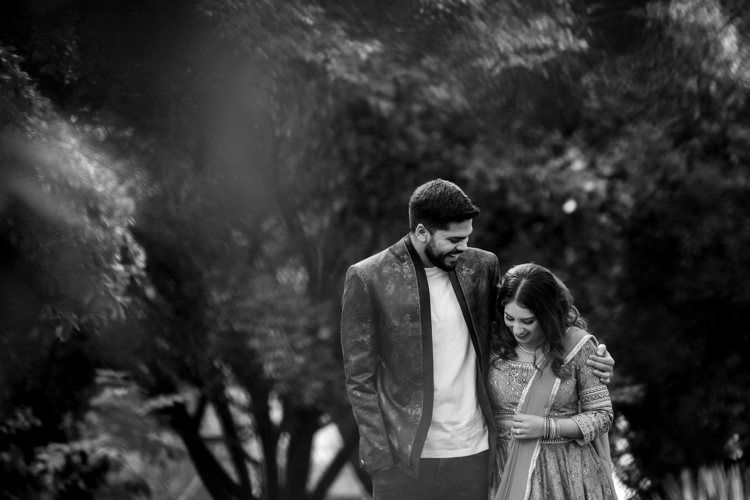 A romantic couple shares an intimate moment together in a scenic black and white outdoor portrait.