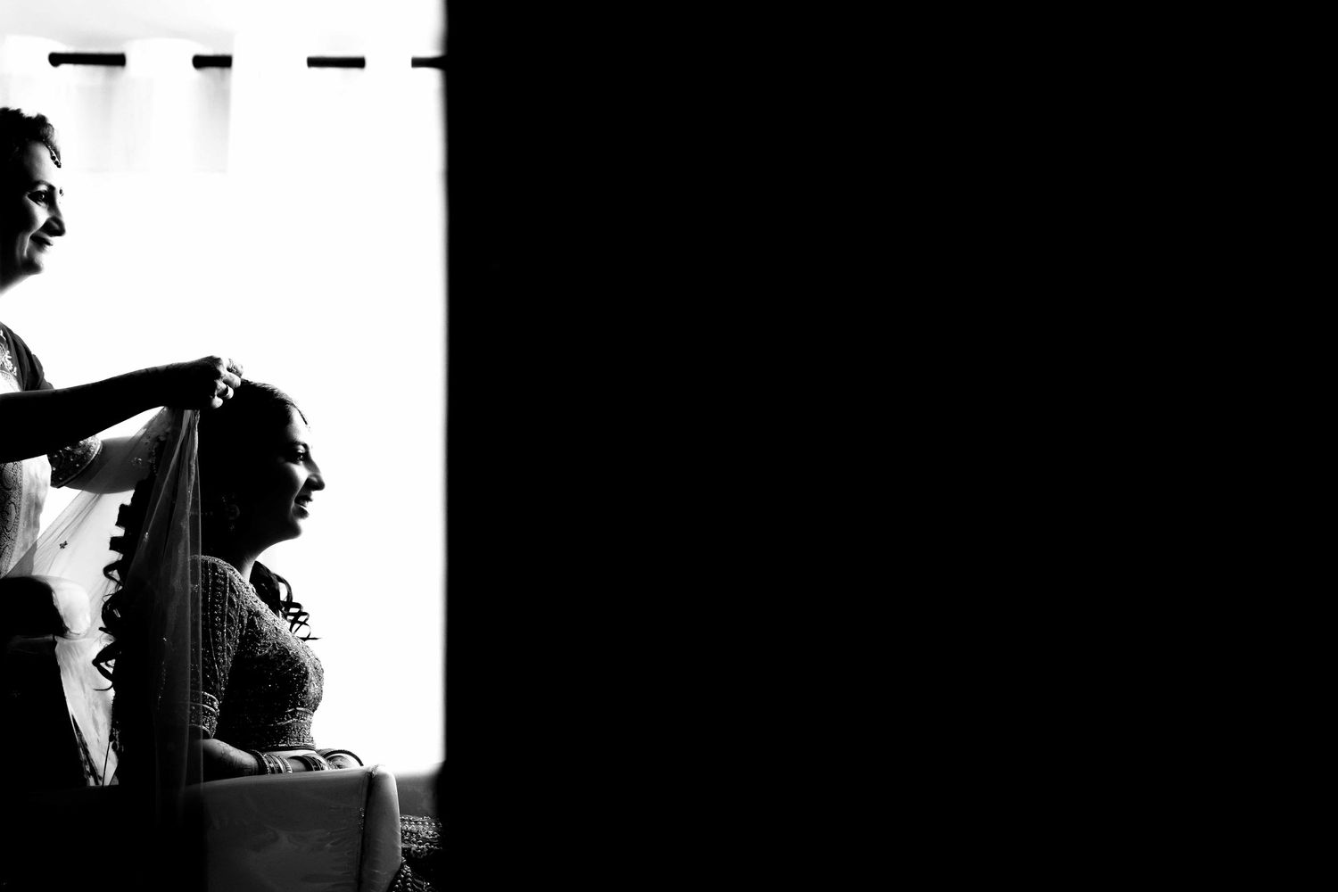 Silhouette of wedding preparation scene against a bright window.
