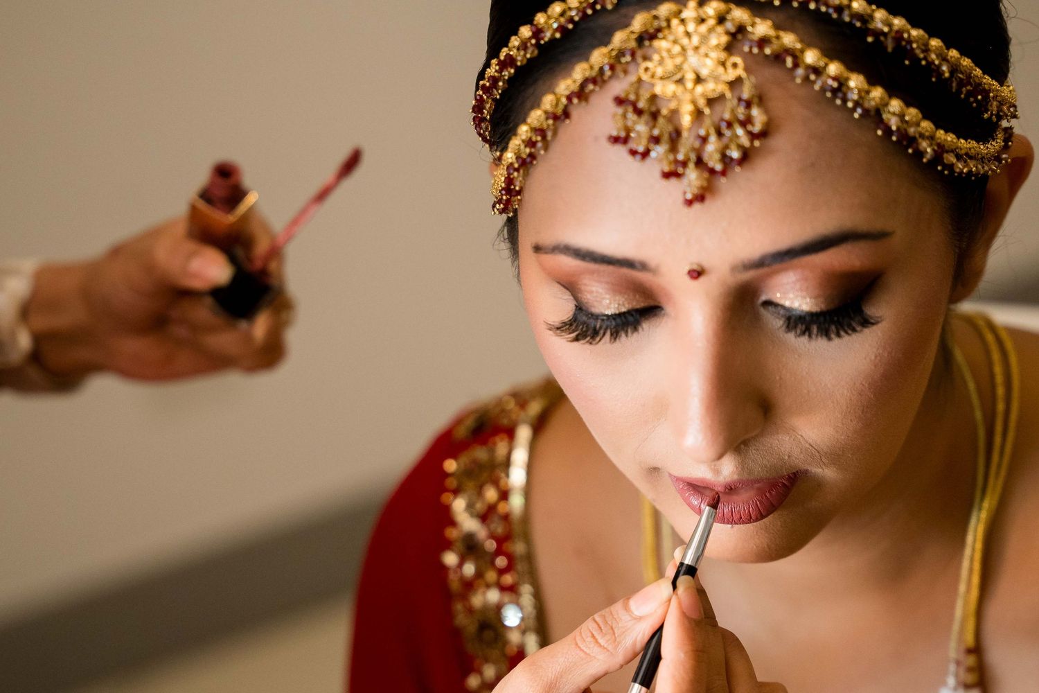 A close-up shot of traditional Indian bridal makeup and jewelry details in warm golden tones.