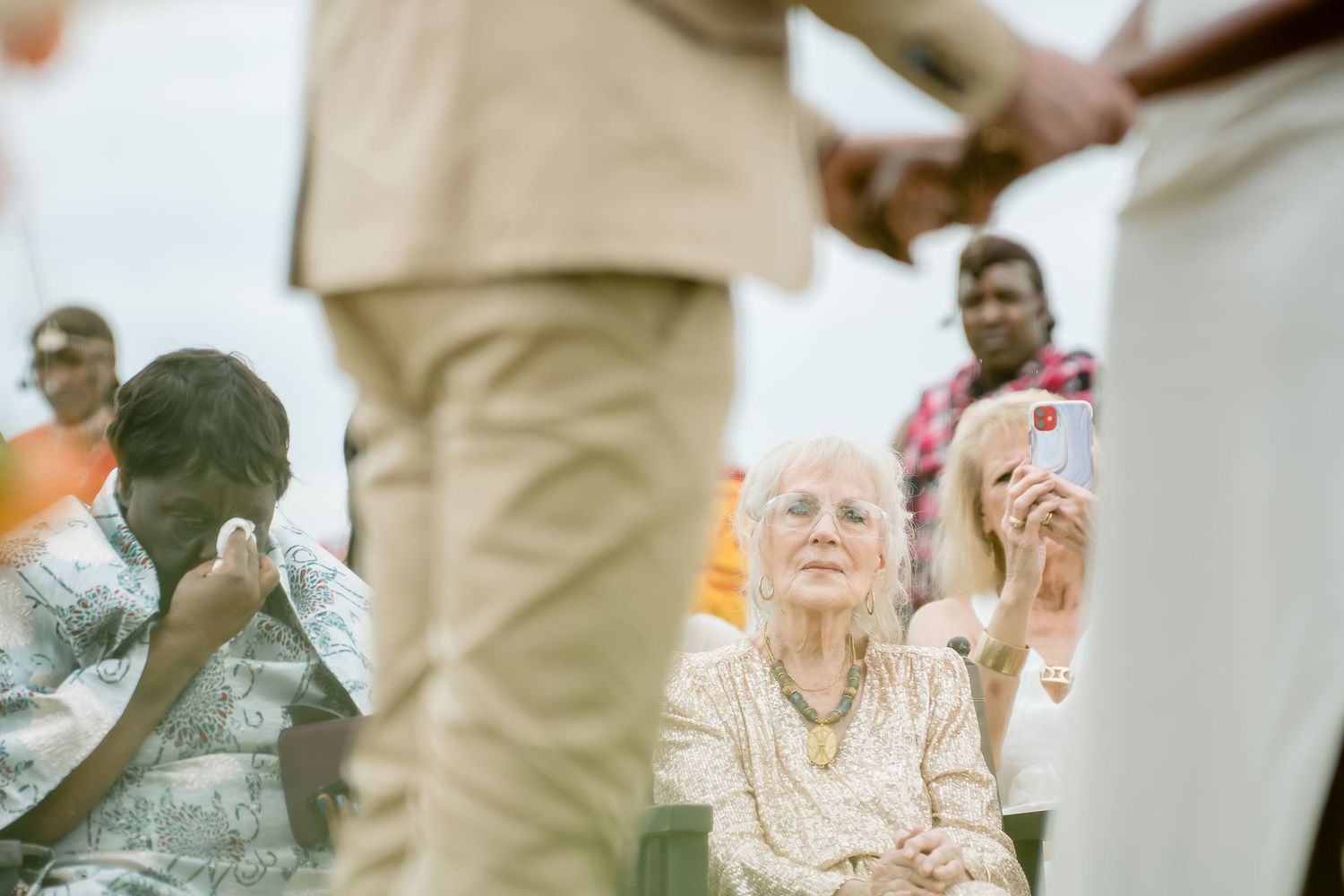 Wedding guests watching ceremony from seats in an outdoor setting.