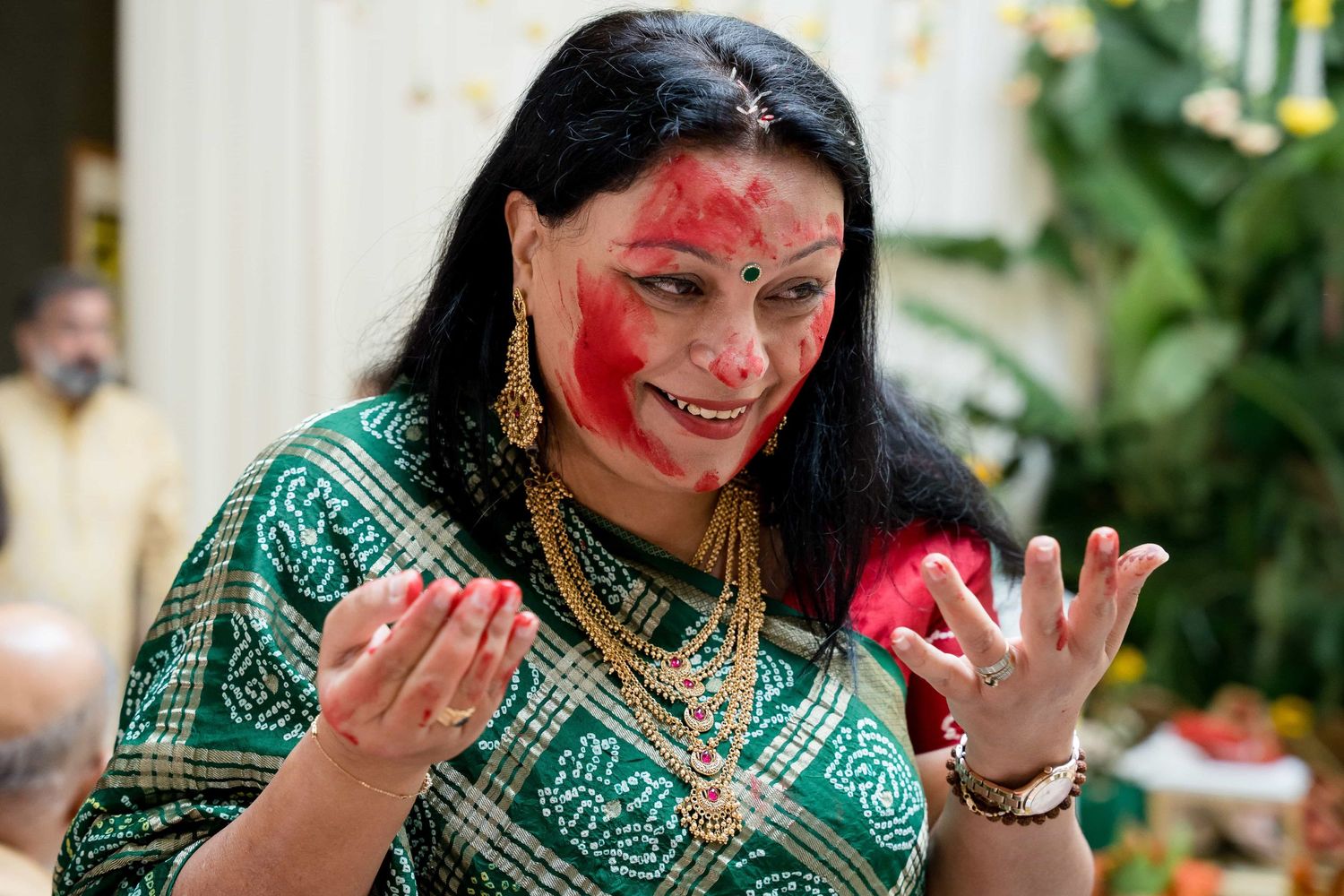 Celebrant covered in red powder smiles during Holi festival celebrations.