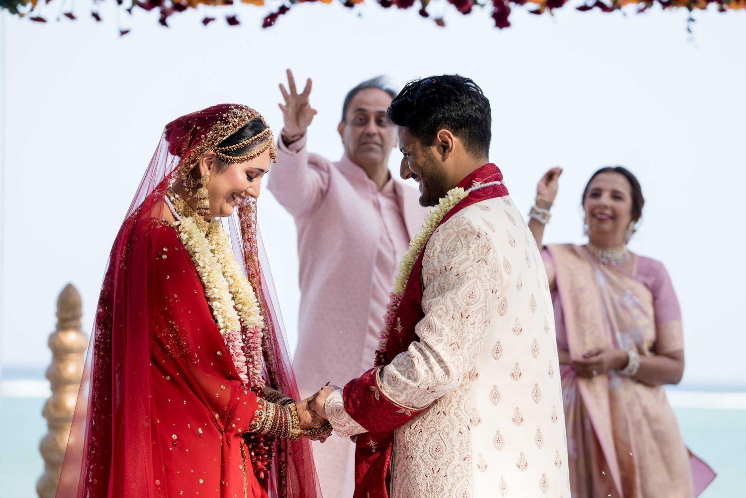 A traditional Indian wedding ceremony with the couple in red and gold attire exchanging vows on a decorated stage.