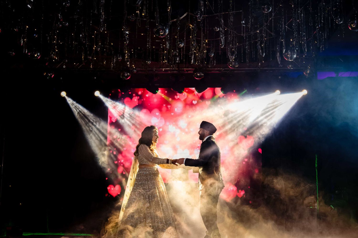 A couple dancing in fog with dramatic red and white lighting creating a romantic silhouette.