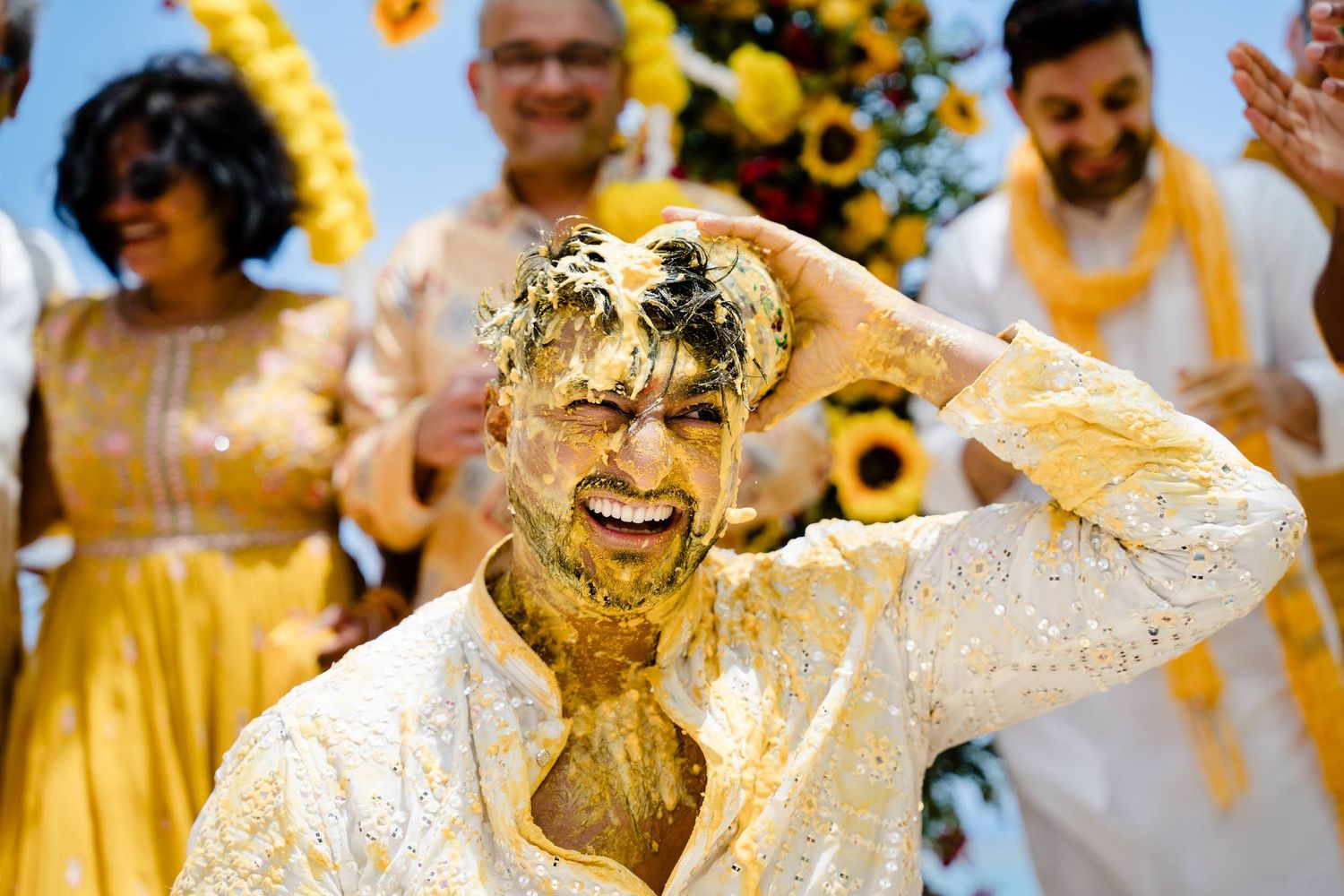 Joyful wedding celebration with guests wearing yellow attire and dancing during a festive ceremony.