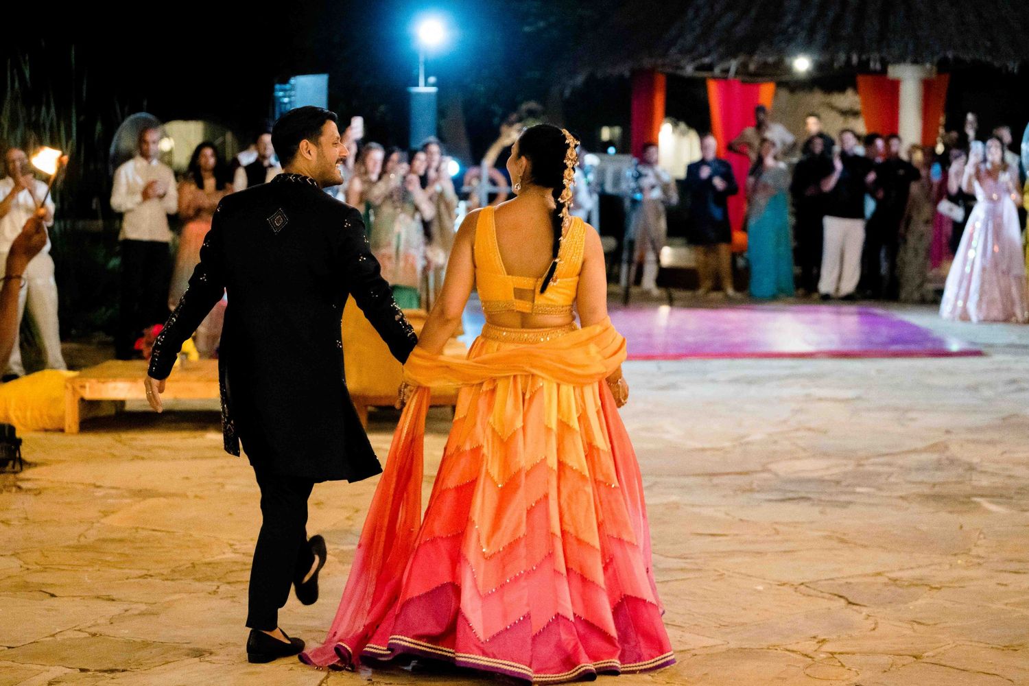 Wedding couples dance on an illuminated outdoor dance floor during an evening reception celebration.