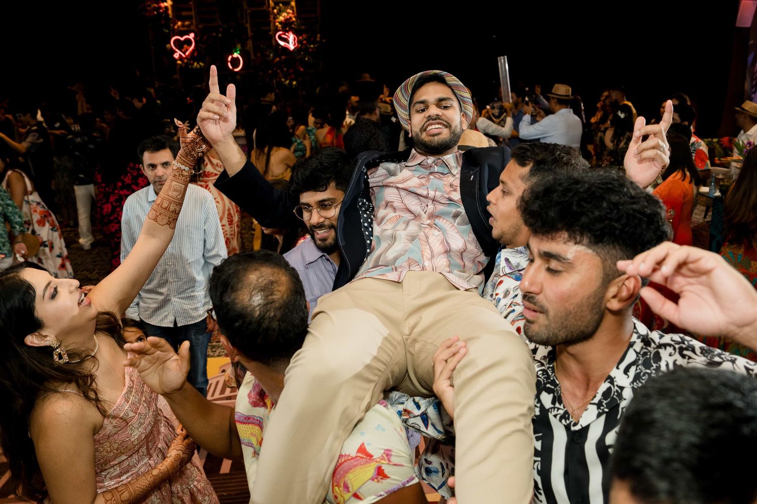 Partygoer celebrates while being lifted by a crowd during an energetic dance celebration at a nighttime event.