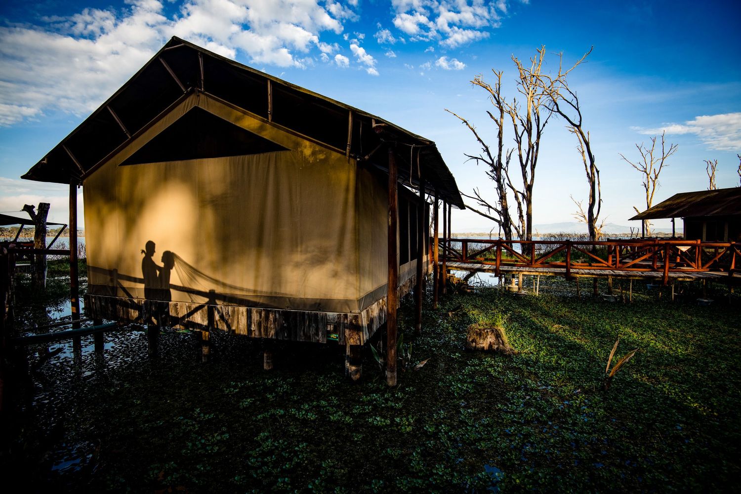 Rustic wooden buildings silhouetted against a dramatic blue sky with puffy white clouds.