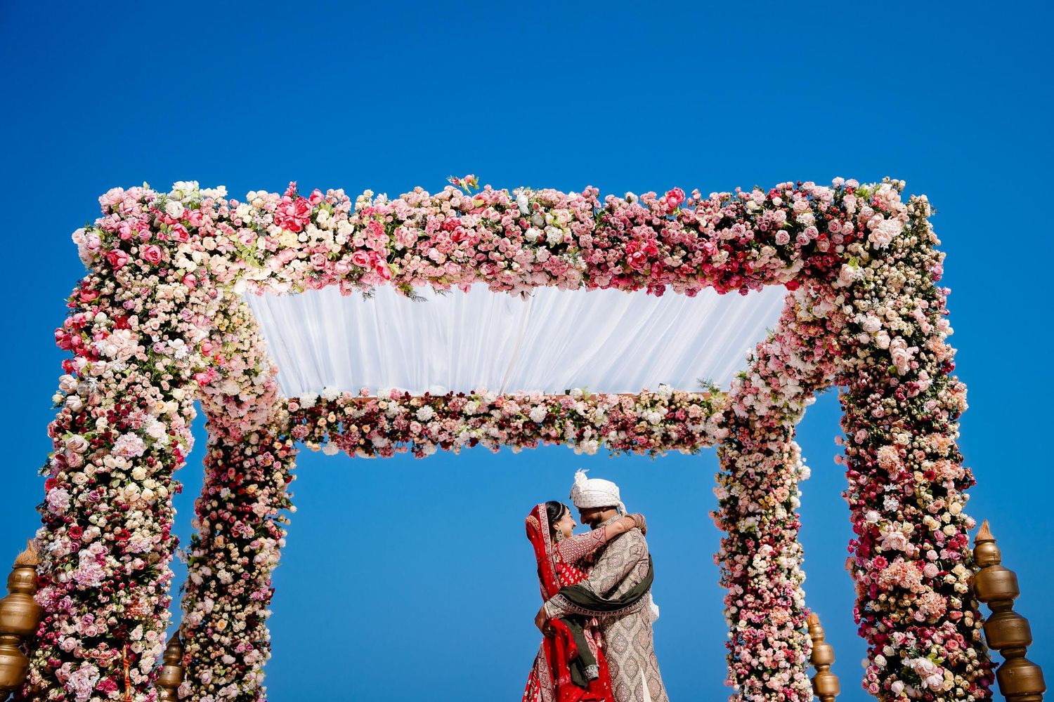 A series of connected white canopy tents with floral decorations against a bright blue sky.