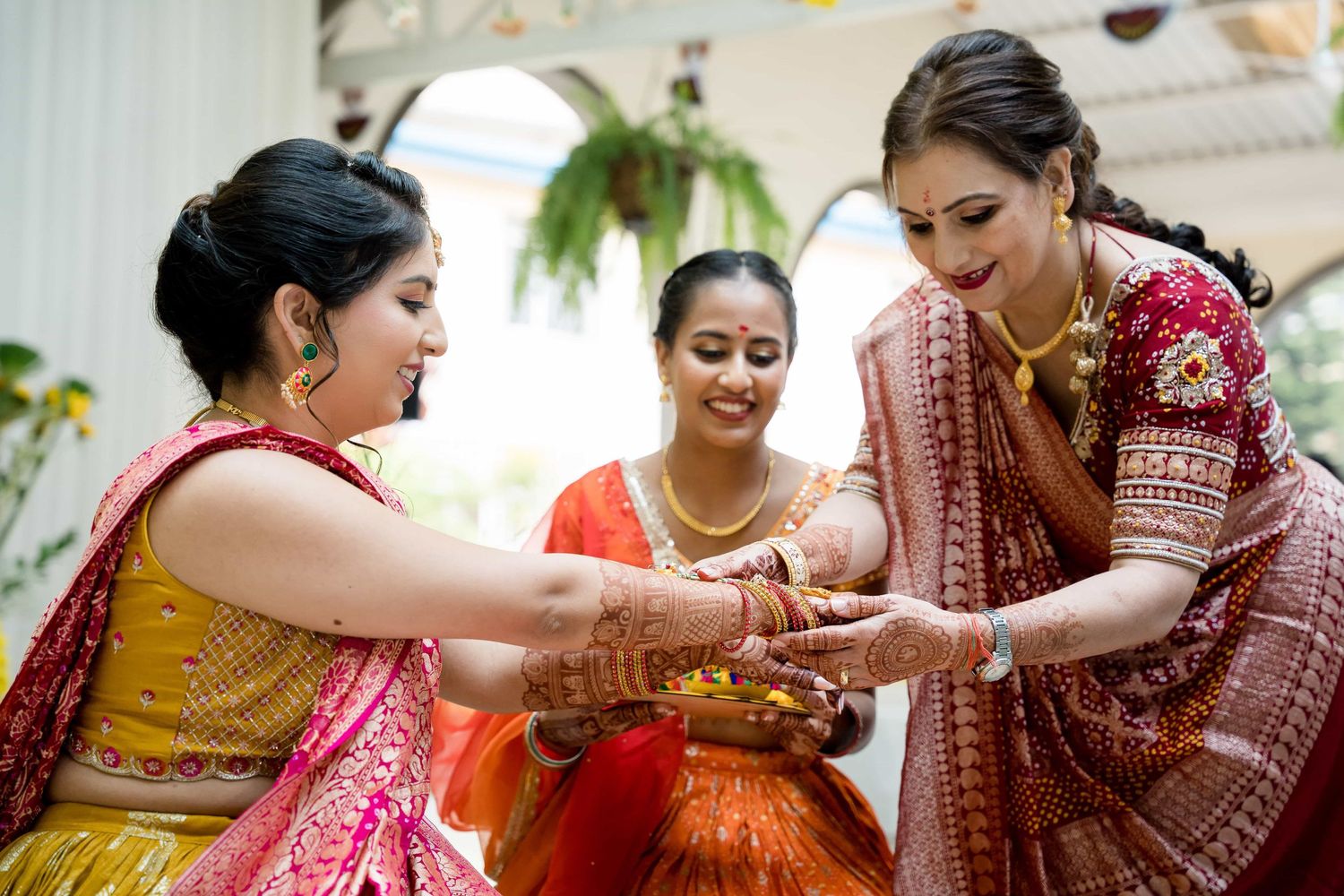 Women in colorful saris perform traditional ritual with henna-decorated hands.