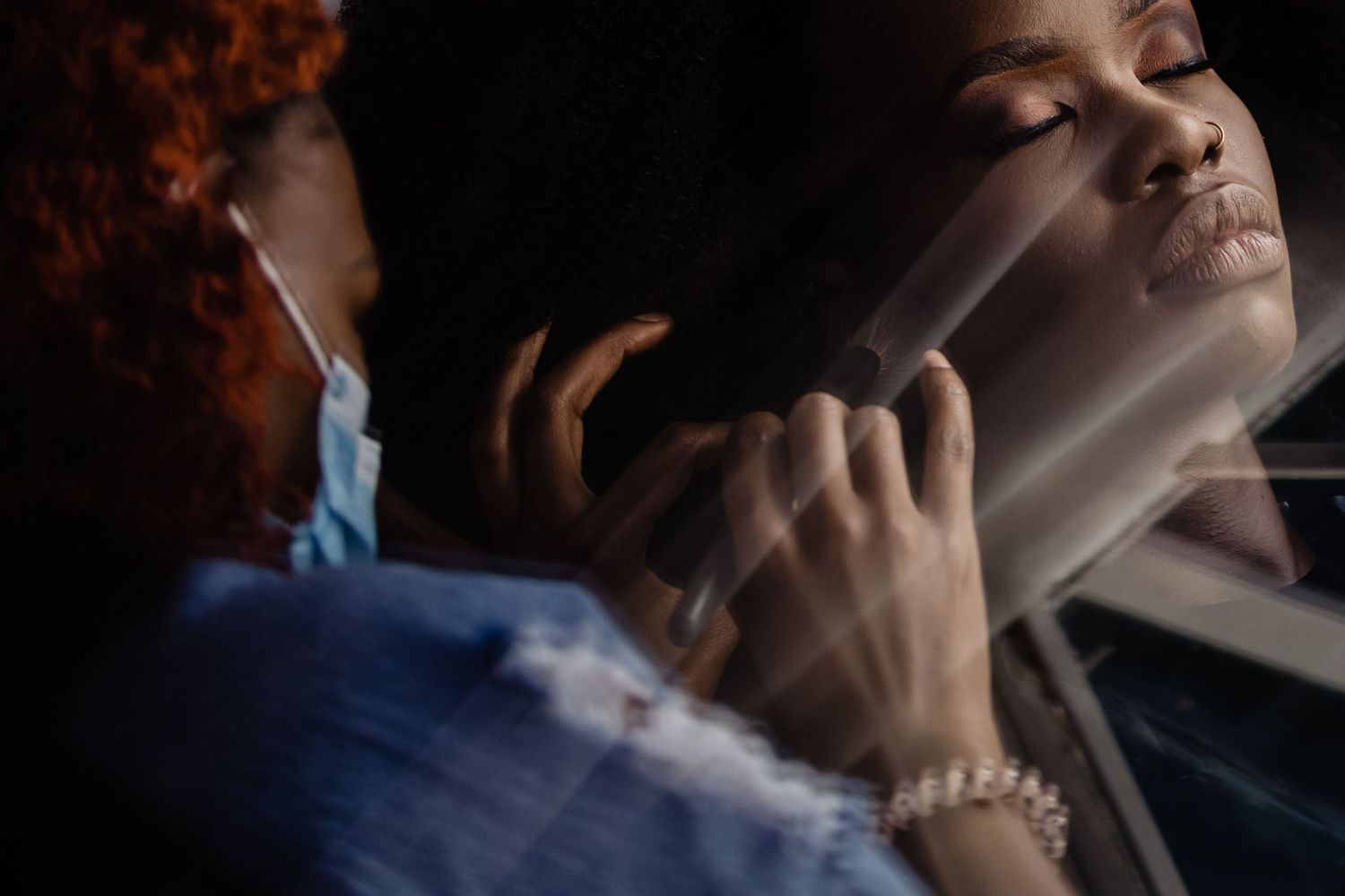 Moody portrait showing reflections in a car window during wedding preparations.