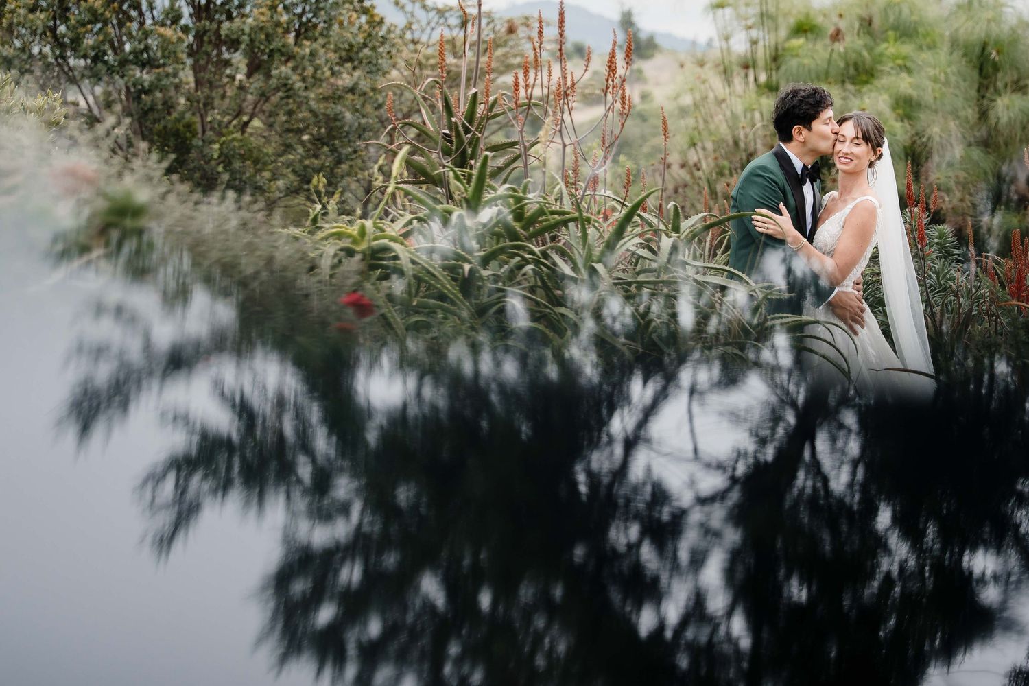 A couple shares an intimate moment in a lush garden setting during their wedding photo session.