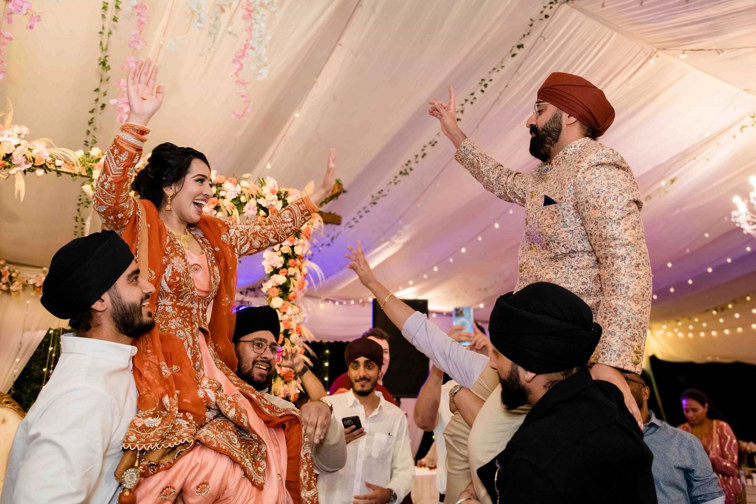 Joyful dance celebration at a traditional Indian wedding with colorful outfits and decor.