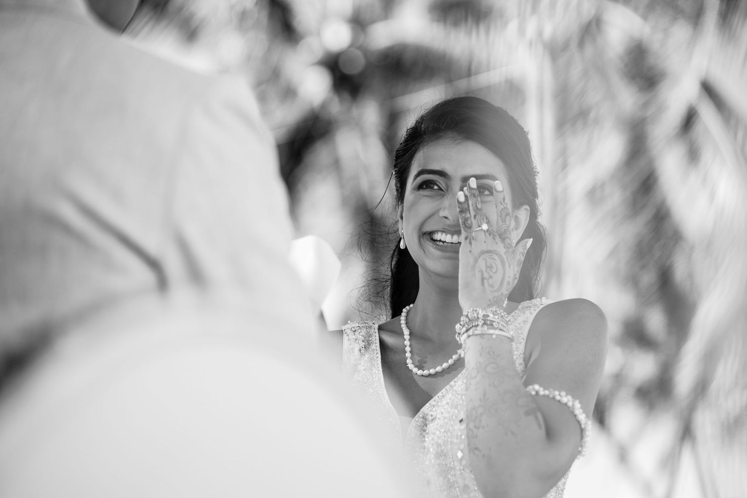 Black and white candid wedding moment with pearl necklace detail.