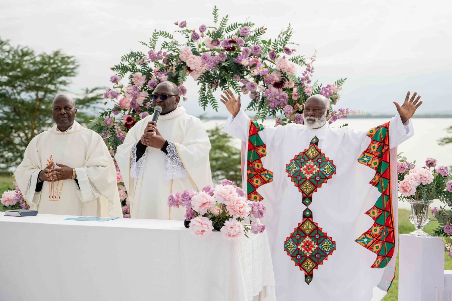 An altar decorated with pink floral arrangements and traditional African patterns during a wedding ceremony.