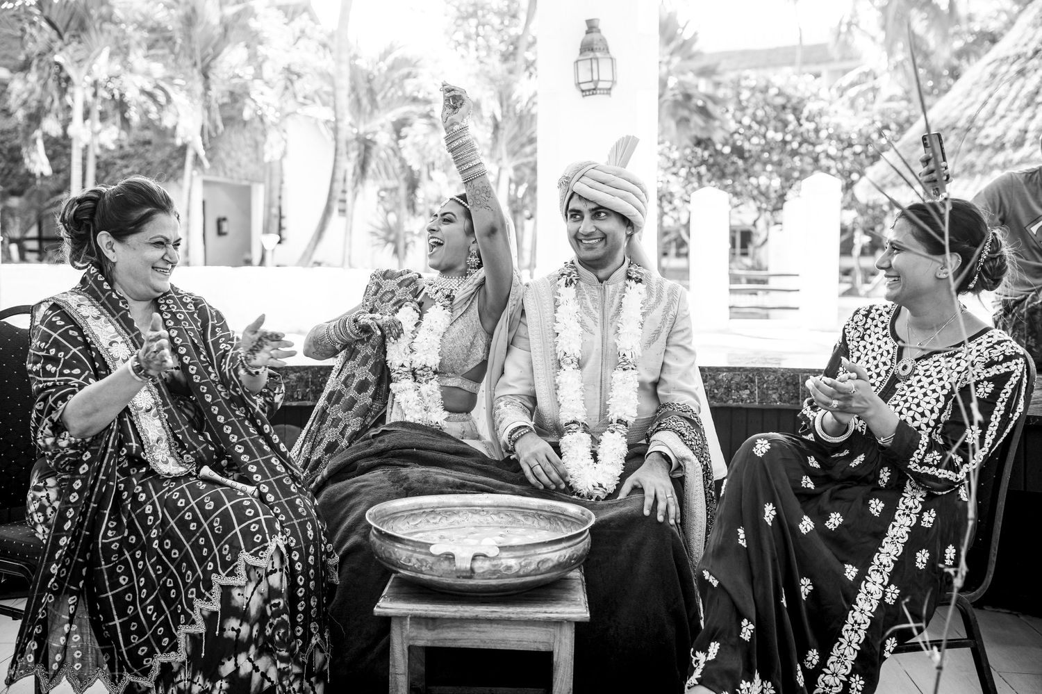 Black and white image of people in traditional Indian attire seated for a wedding ceremony.
