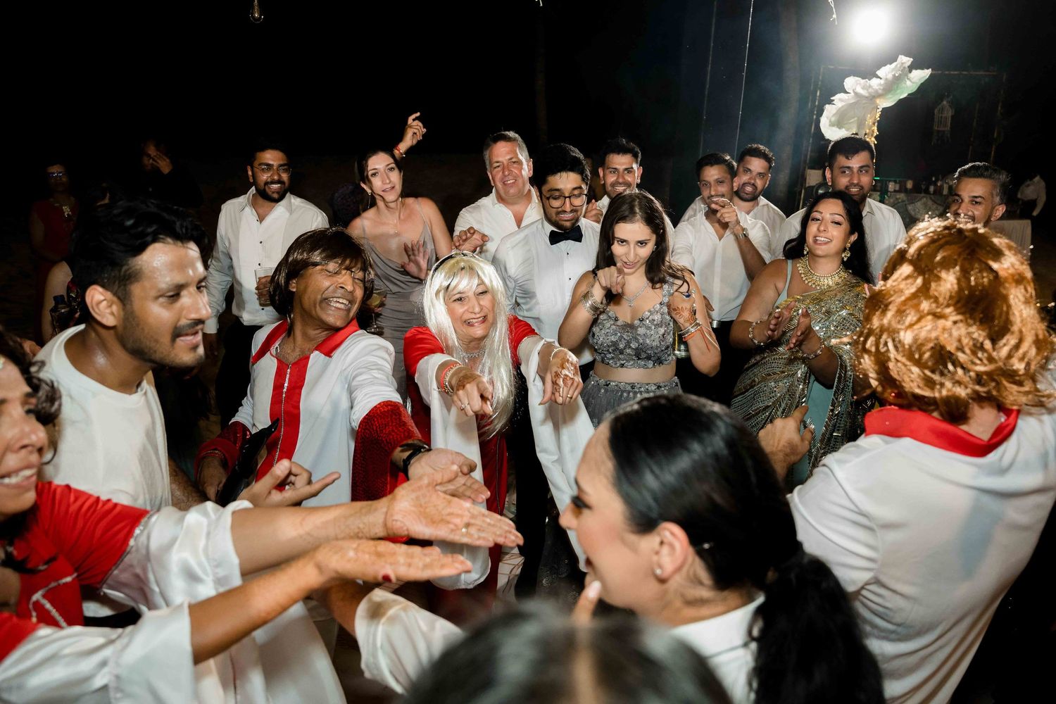 Large group of people in red and white outfits dancing and celebrating together at a party.