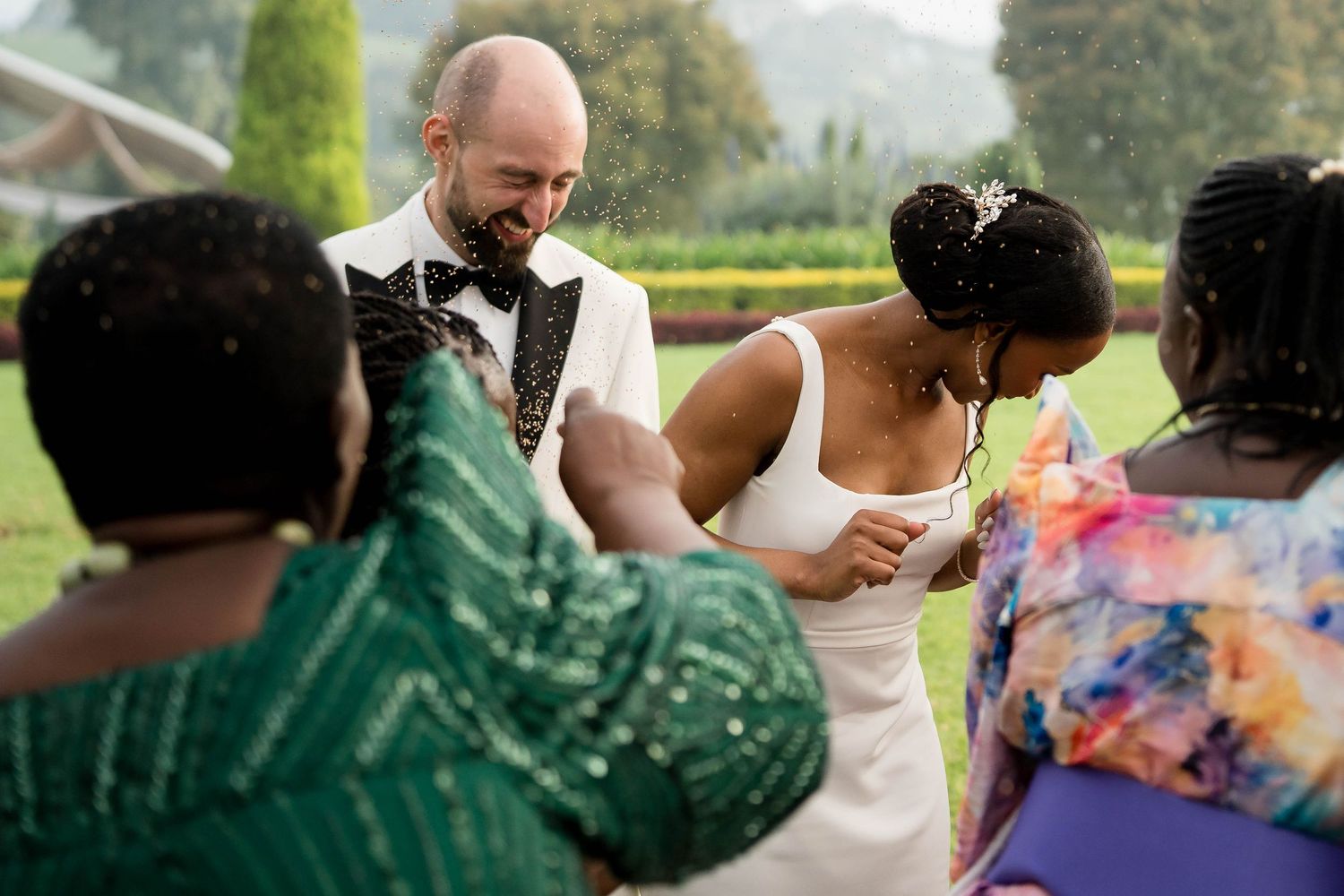 Guests enjoying a festive outdoor wedding reception with colorful attire and natural scenery in the background.