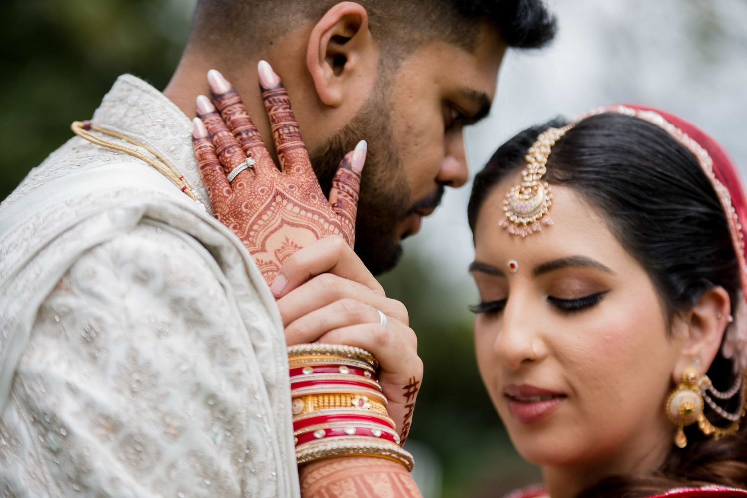 Close-up of traditional Indian wedding jewelry and henna details during ceremony.