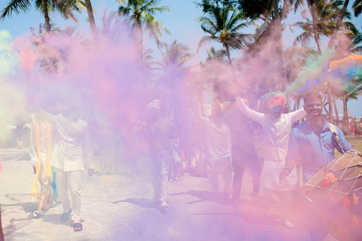 Colorful powder explodes in slow motion during a festive celebration with palm trees in the background.