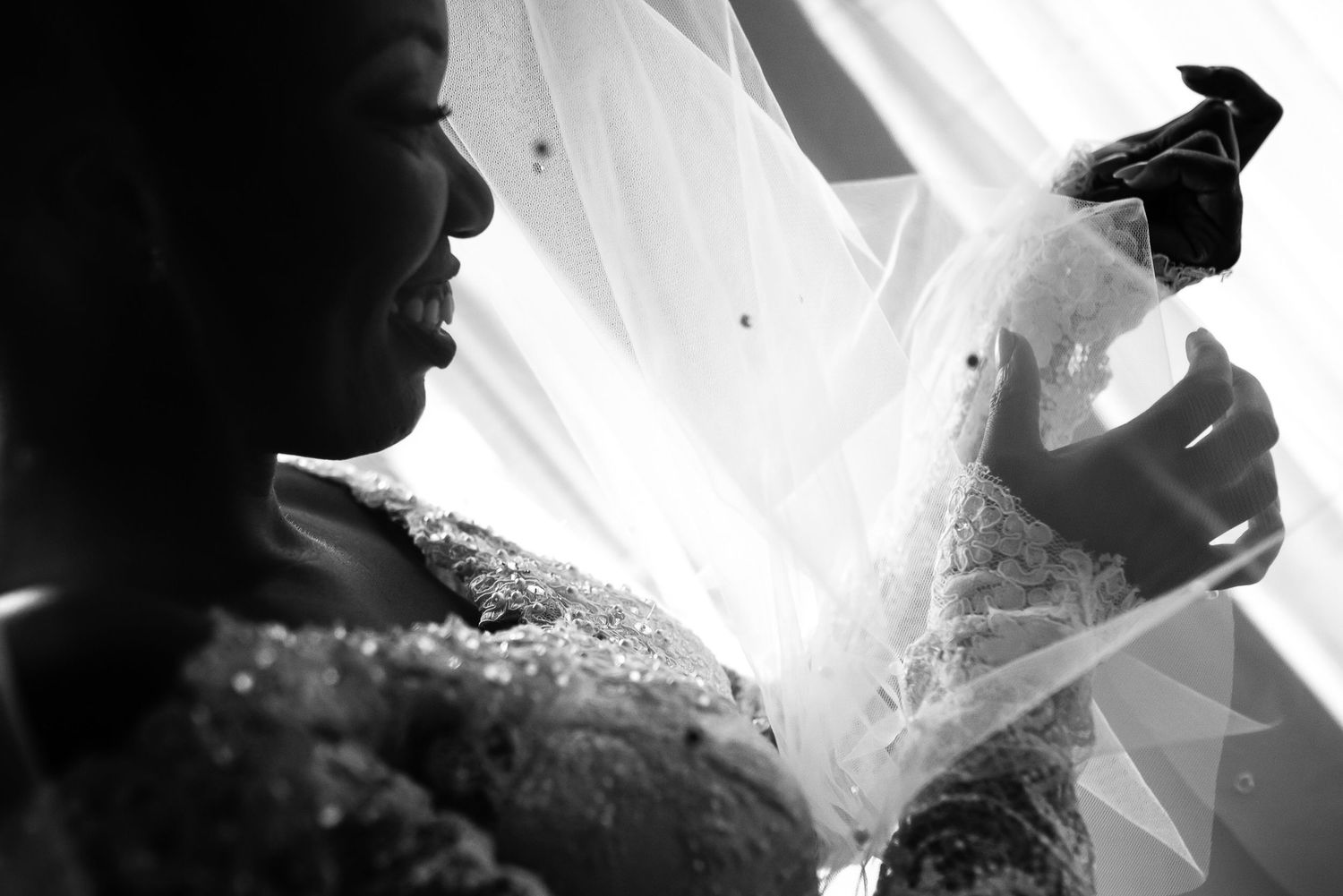 Ethereal bridal veil flows dramatically in black and white wedding portrait.