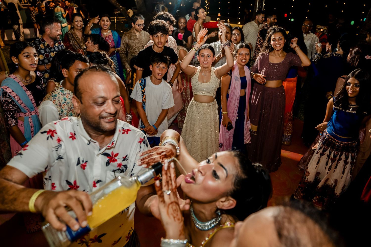 Energetic dance party with guests celebrating on a crowded dance floor at night.
