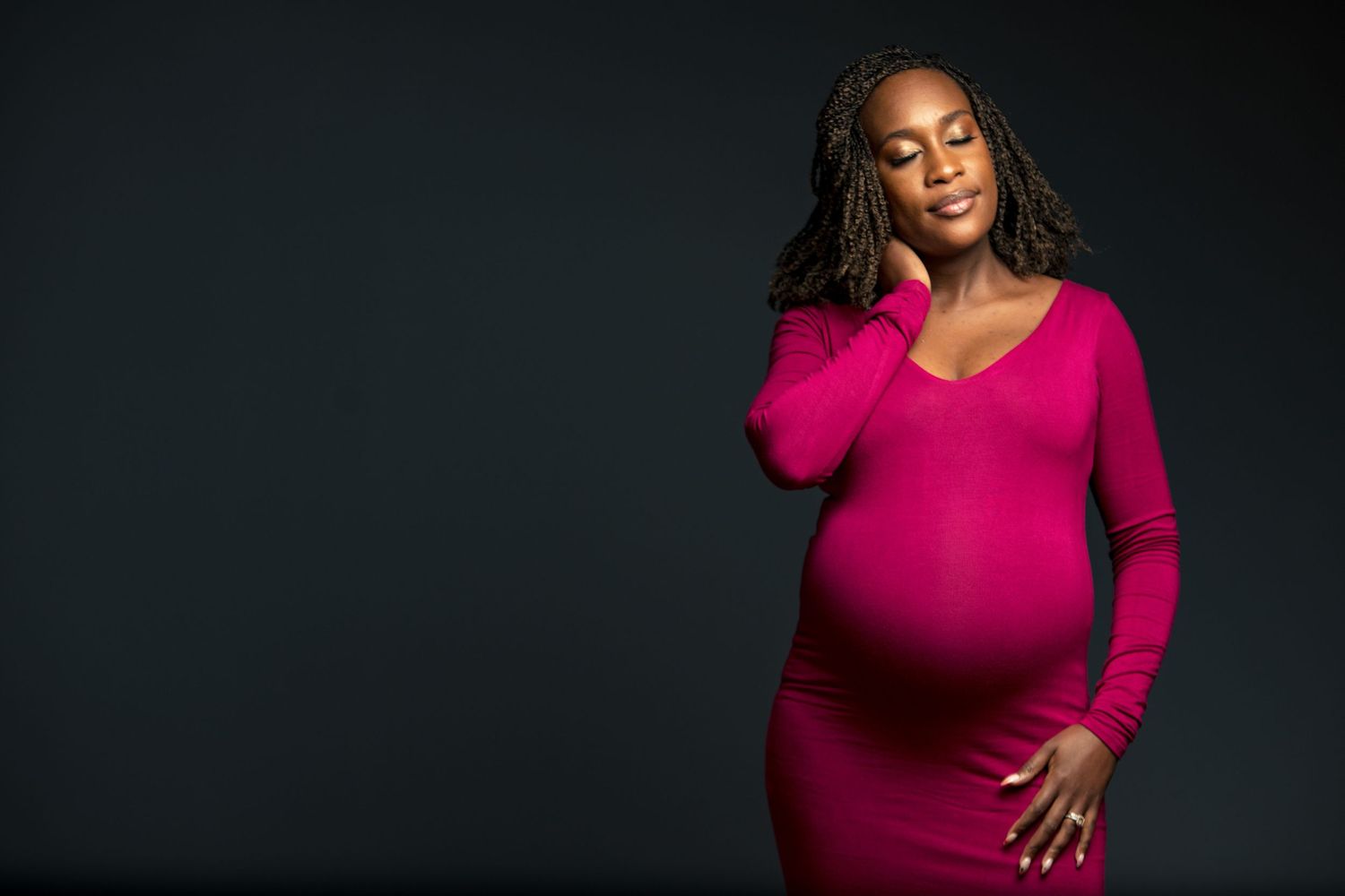 Woman in bright pink dress poses confidently against dark background in studio portraits.