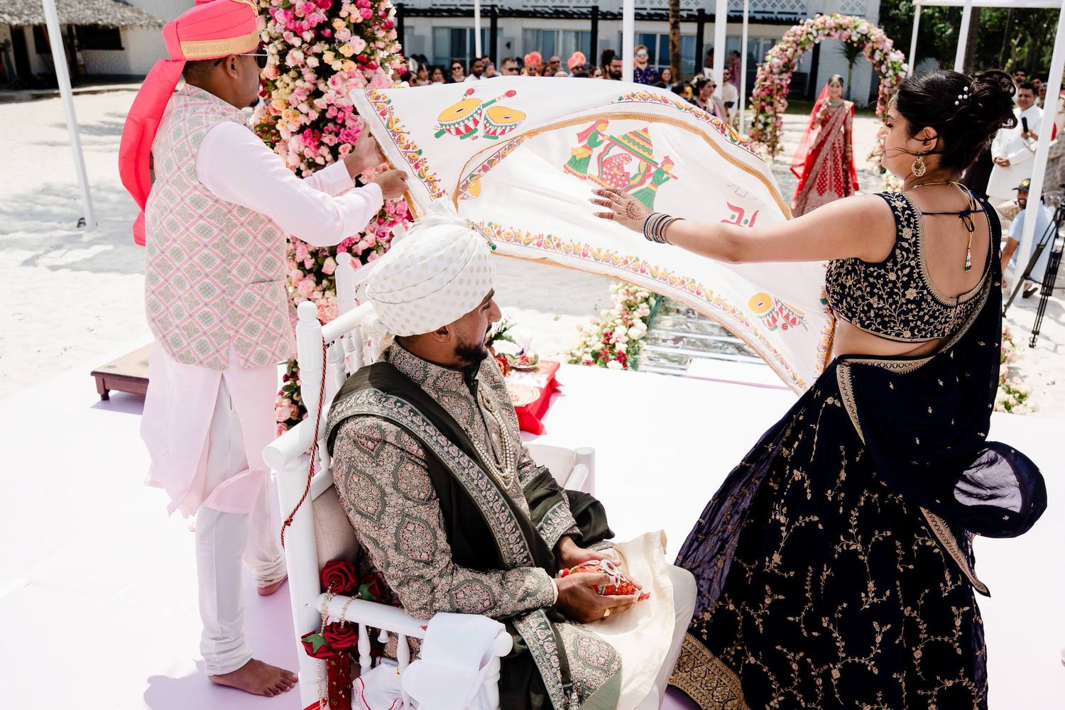 Wedding guests throw pink rose petals in celebration as newlyweds exit their ceremony.