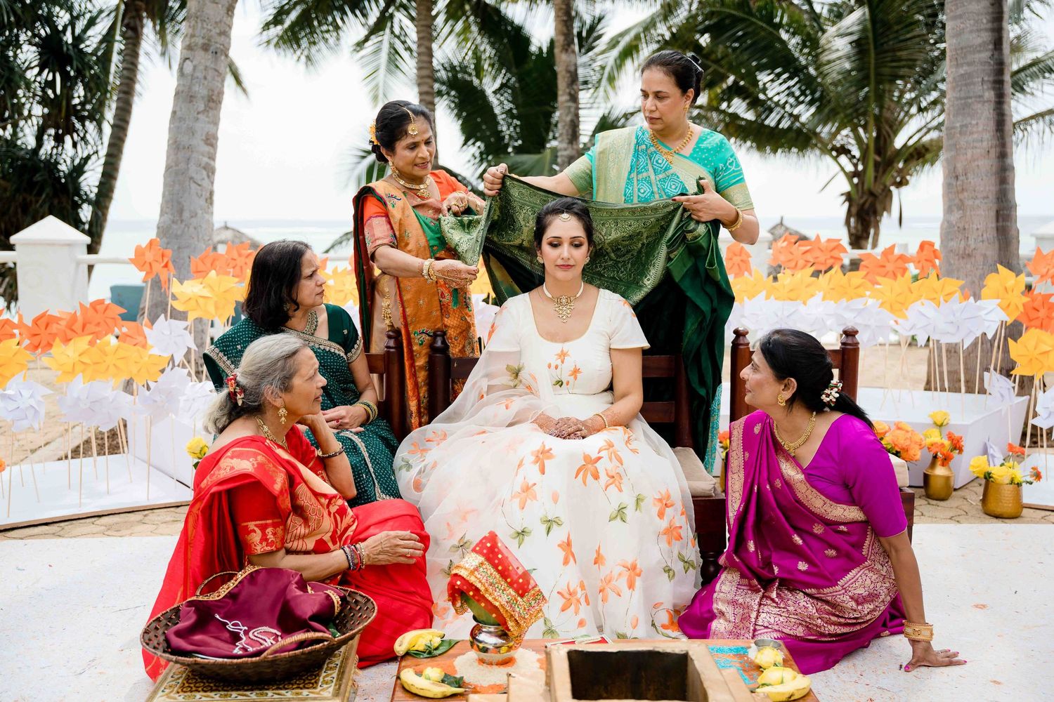 A group of dancers in traditional Indian attire perform a cultural dance routine outdoors under palm trees.