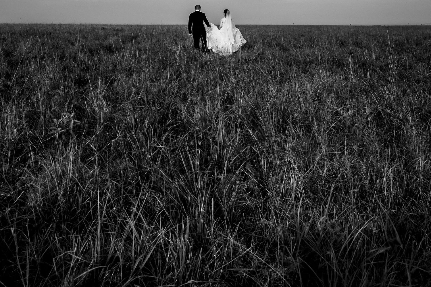 Silhouettes walking along a misty horizon in black and white landscape photography.