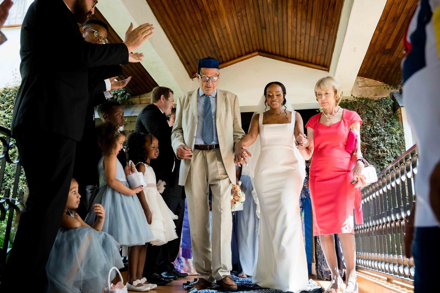 Wedding guests gather on a covered wooden deck during an outdoor celebration.