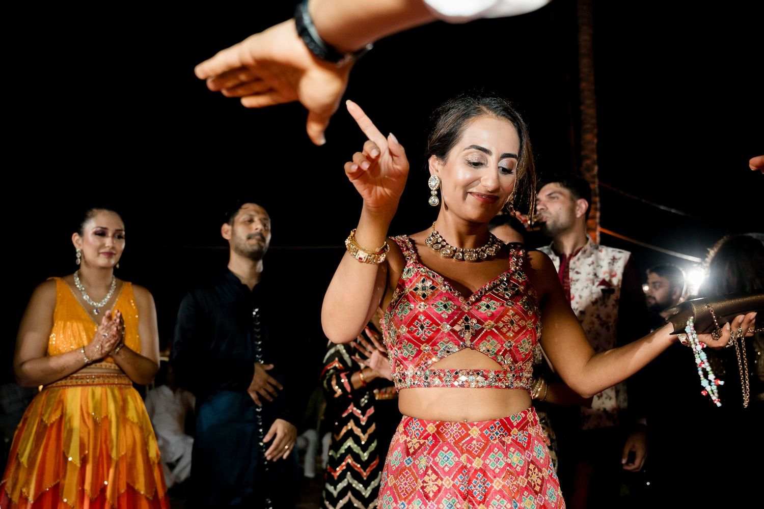 Dancers in colorful traditional Indian attire perform energetic dance moves at a festive celebration.