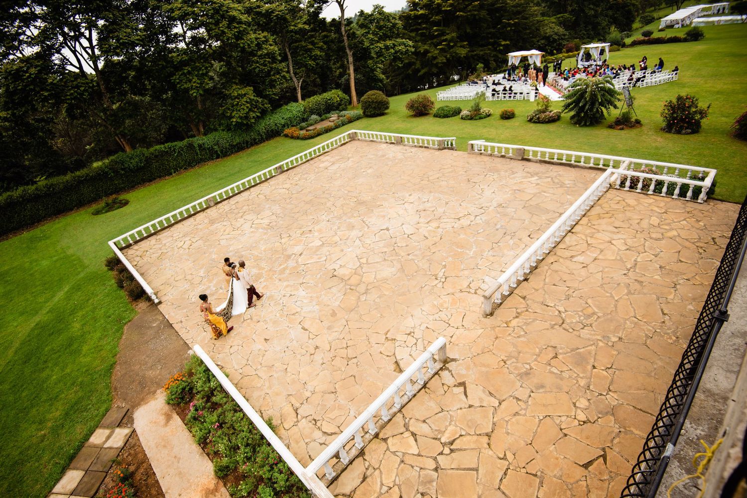Aerial view of a large outdoor equestrian arena with sand footing and white fencing.