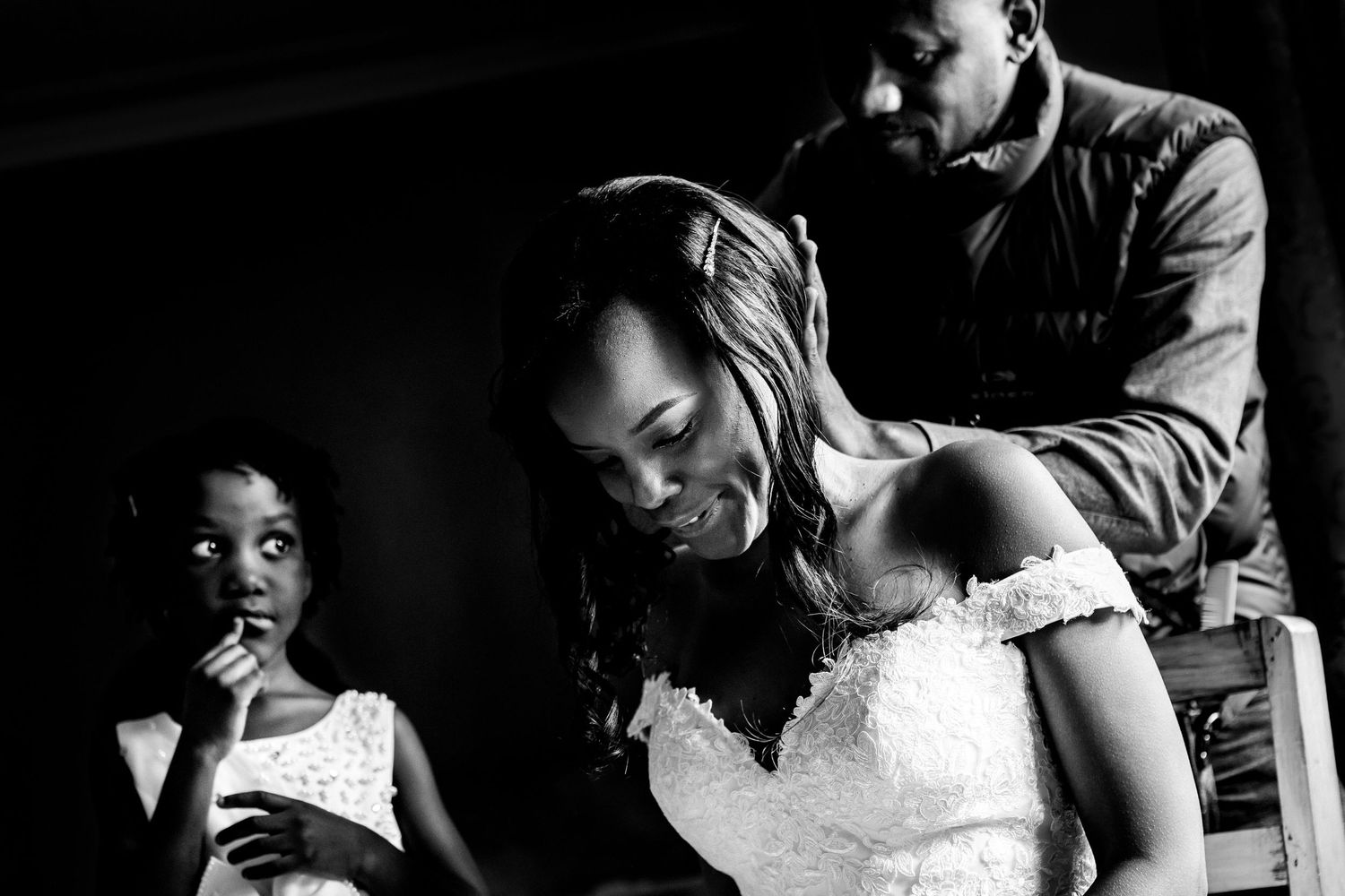 Black and white wedding preparation scene with bridesmaids helping the bride.