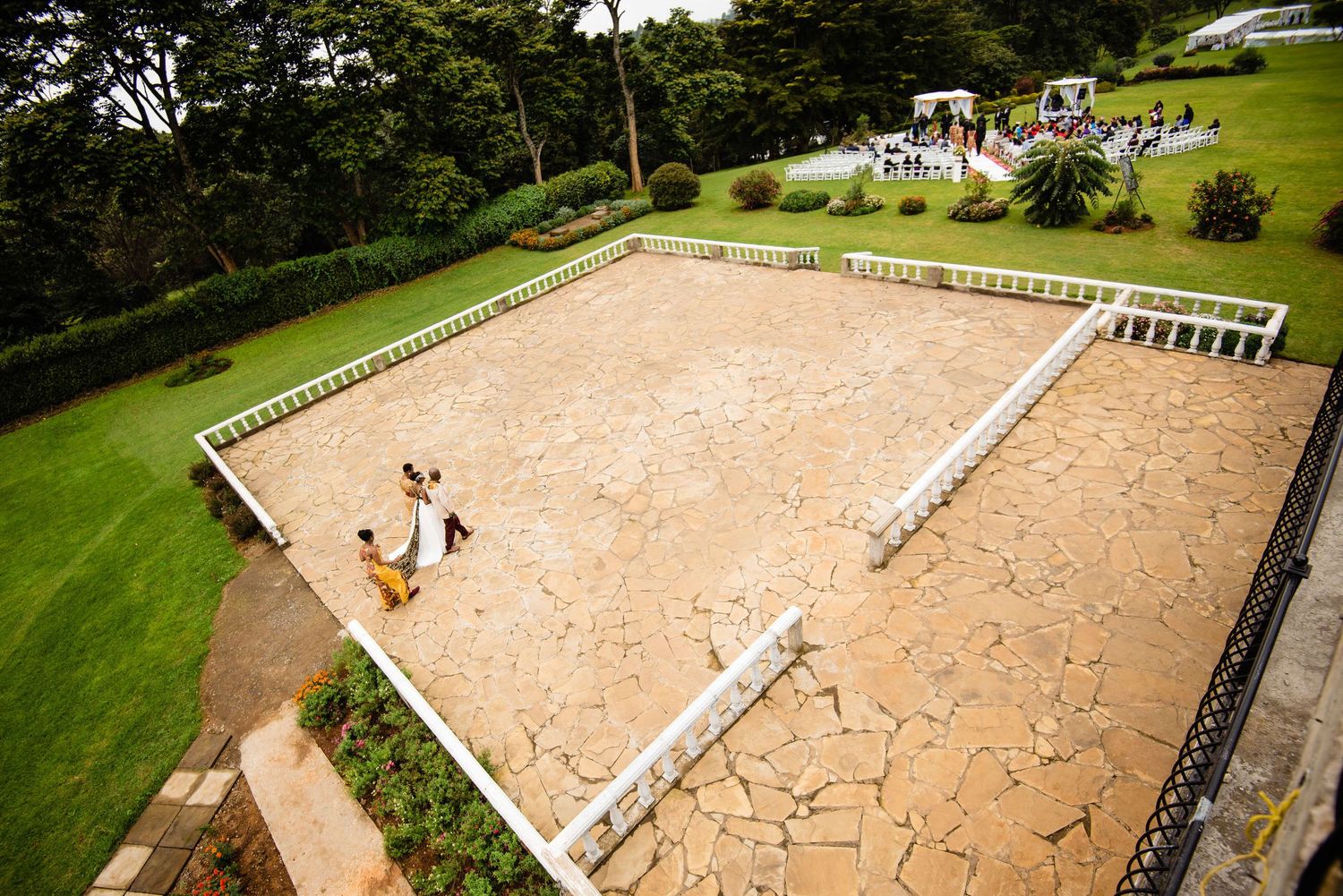 Aerial view of a sandy outdoor event space surrounded by white fencing and green landscape.