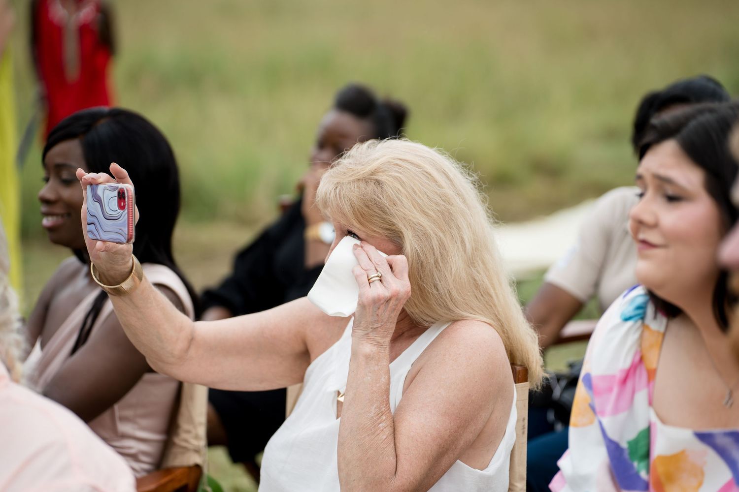 Guests become emotional while capturing photos during outdoor celebration.