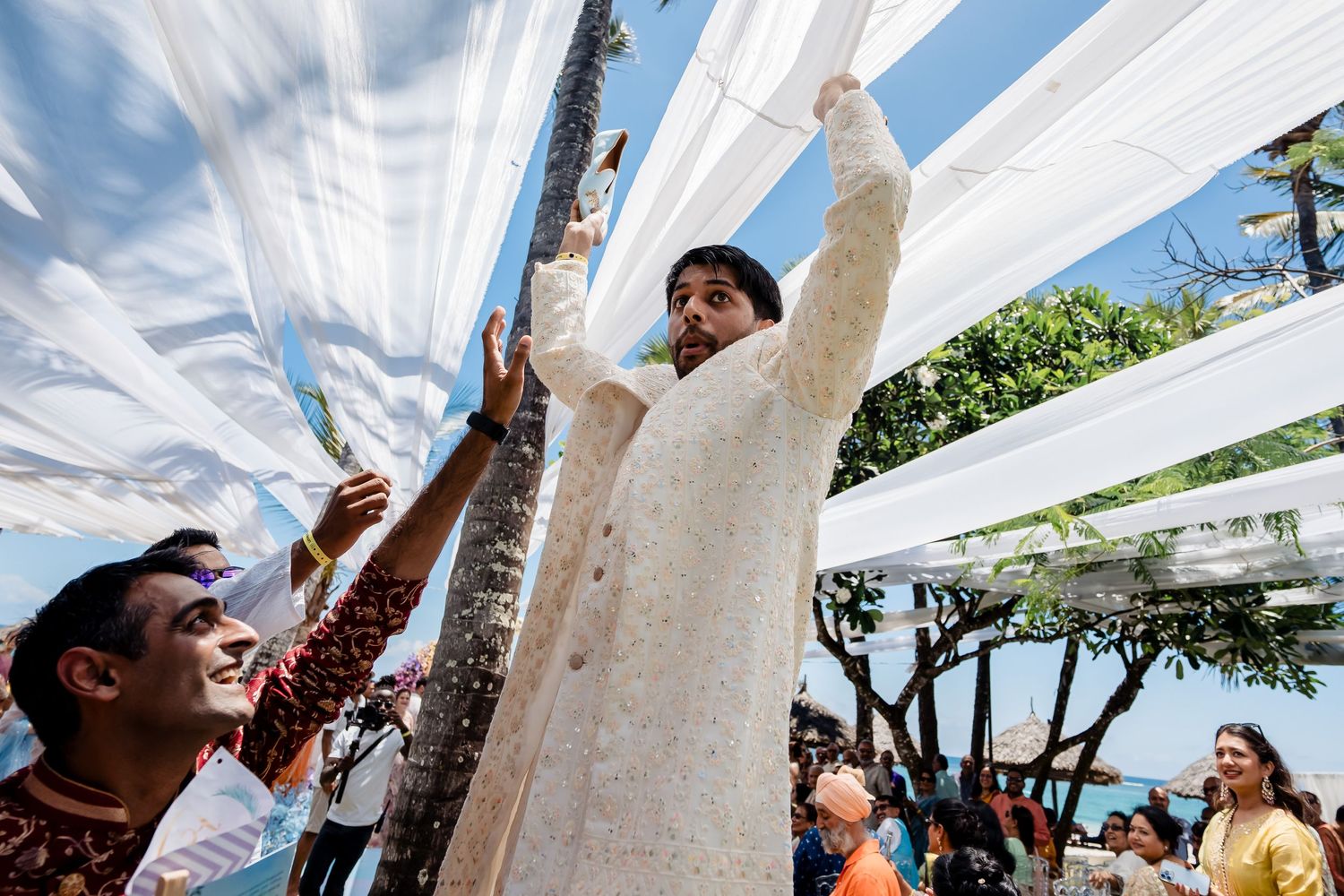 Celebratory moment under white fabric canopy during outdoor wedding ceremony.