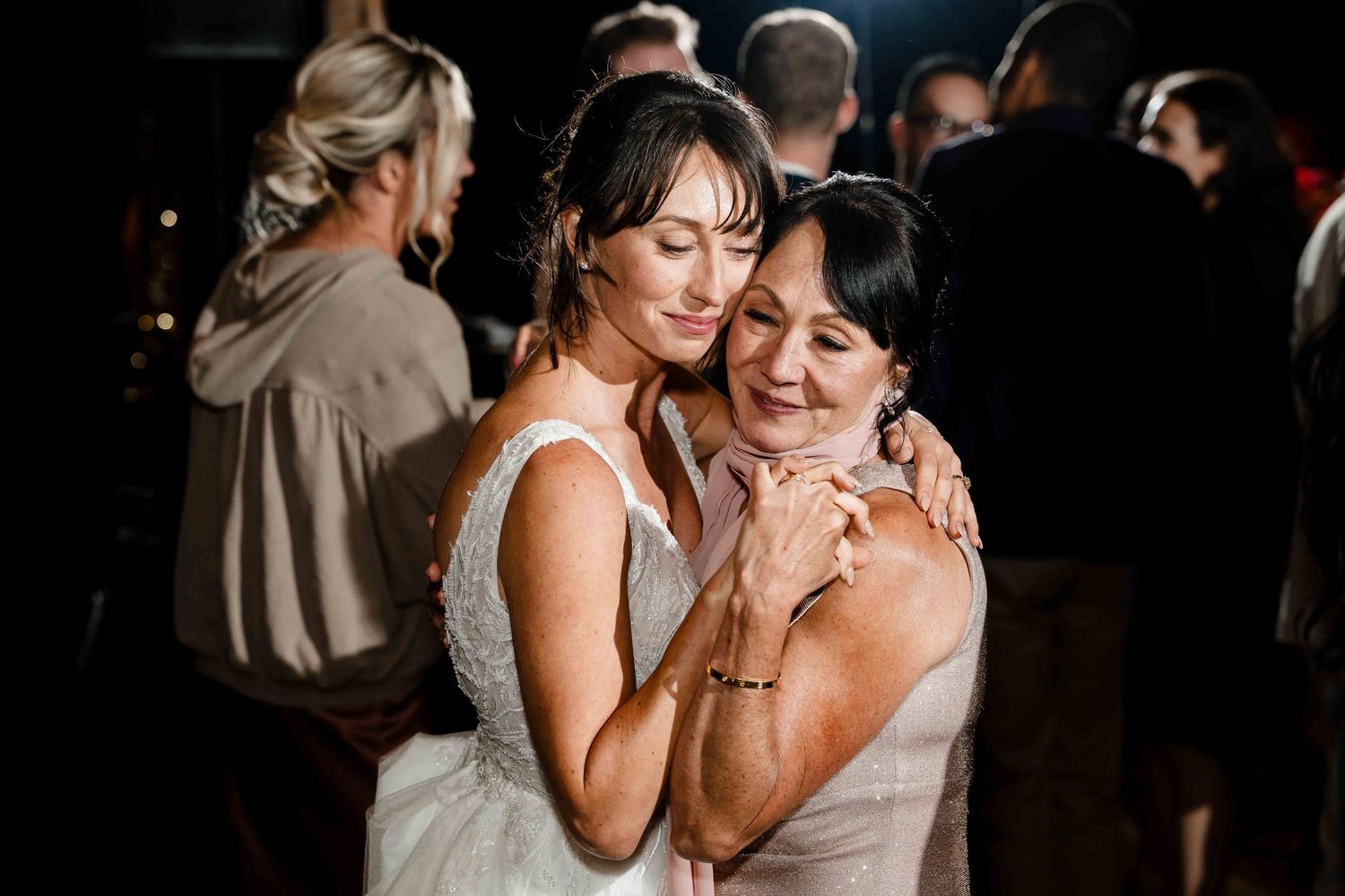 Two people share an intimate embrace while dancing together at an evening celebration event.