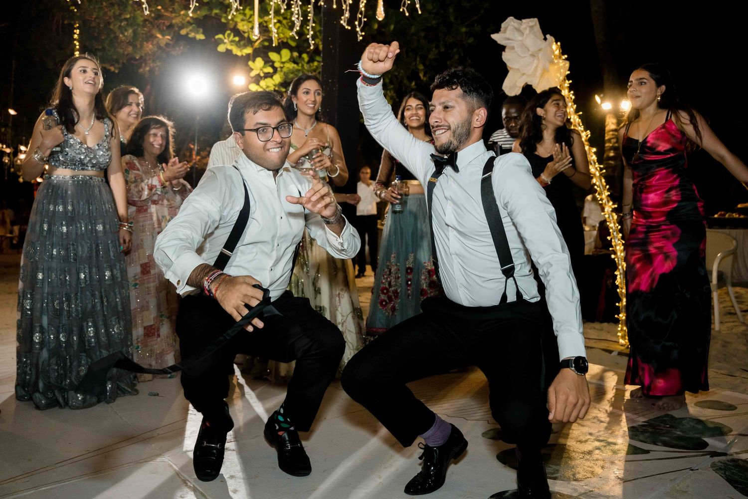 Wedding guests dancing and celebrating on the dance floor during an evening reception party.
