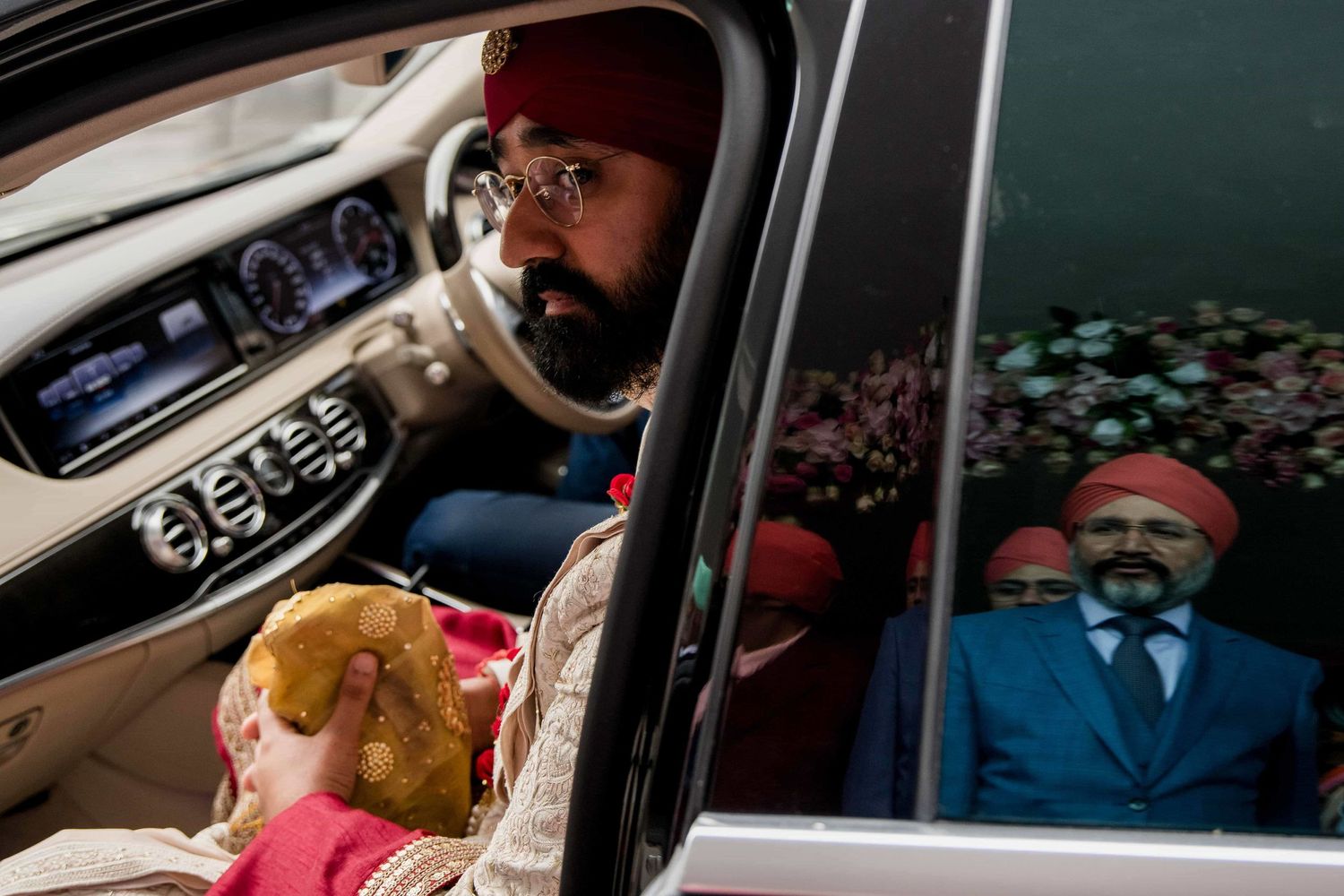View through car window of wedding guests in traditional Sikh attire.