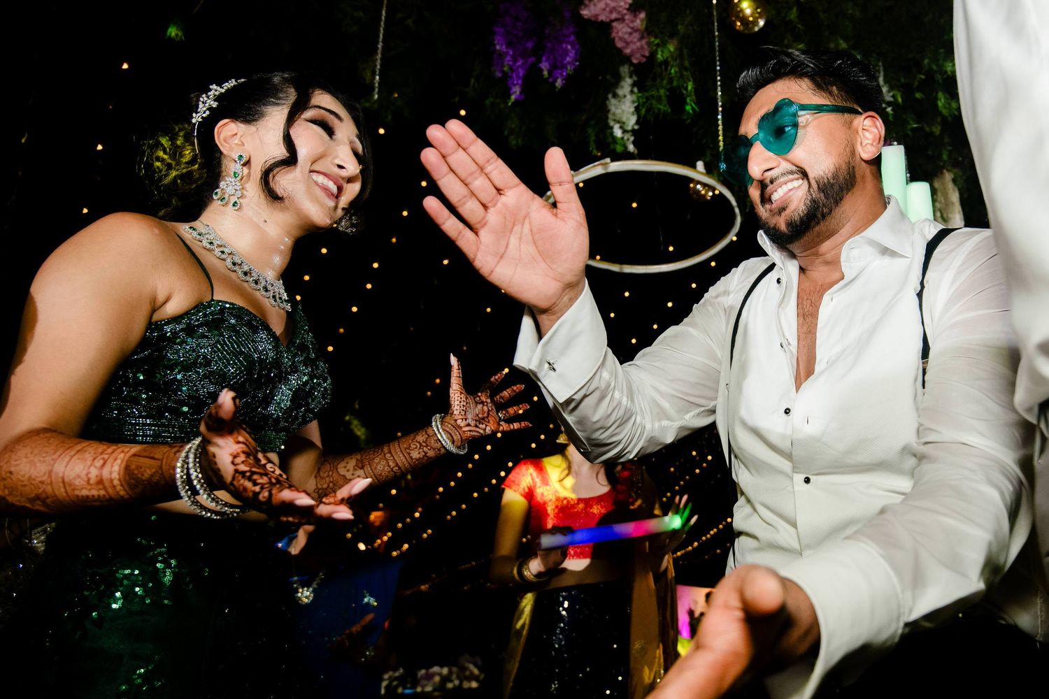People dancing and celebrating at a lively nightclub party with colorful lights and confetti in the background.