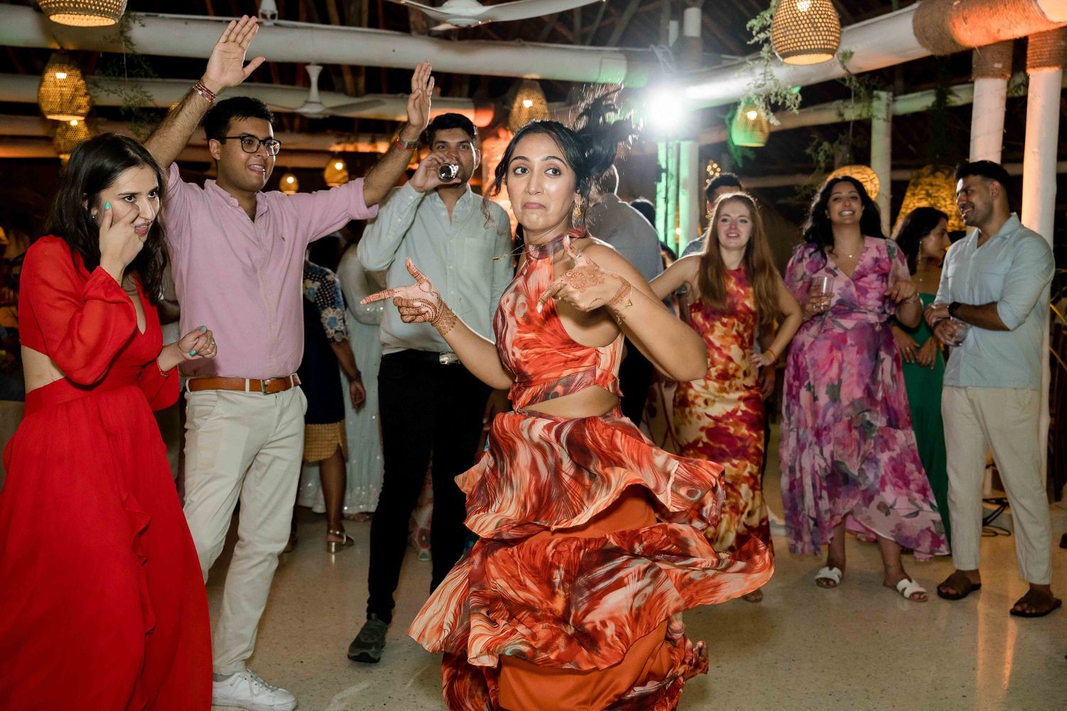 People dancing together at a lively party or celebration with colorful outfits and decorative lighting.